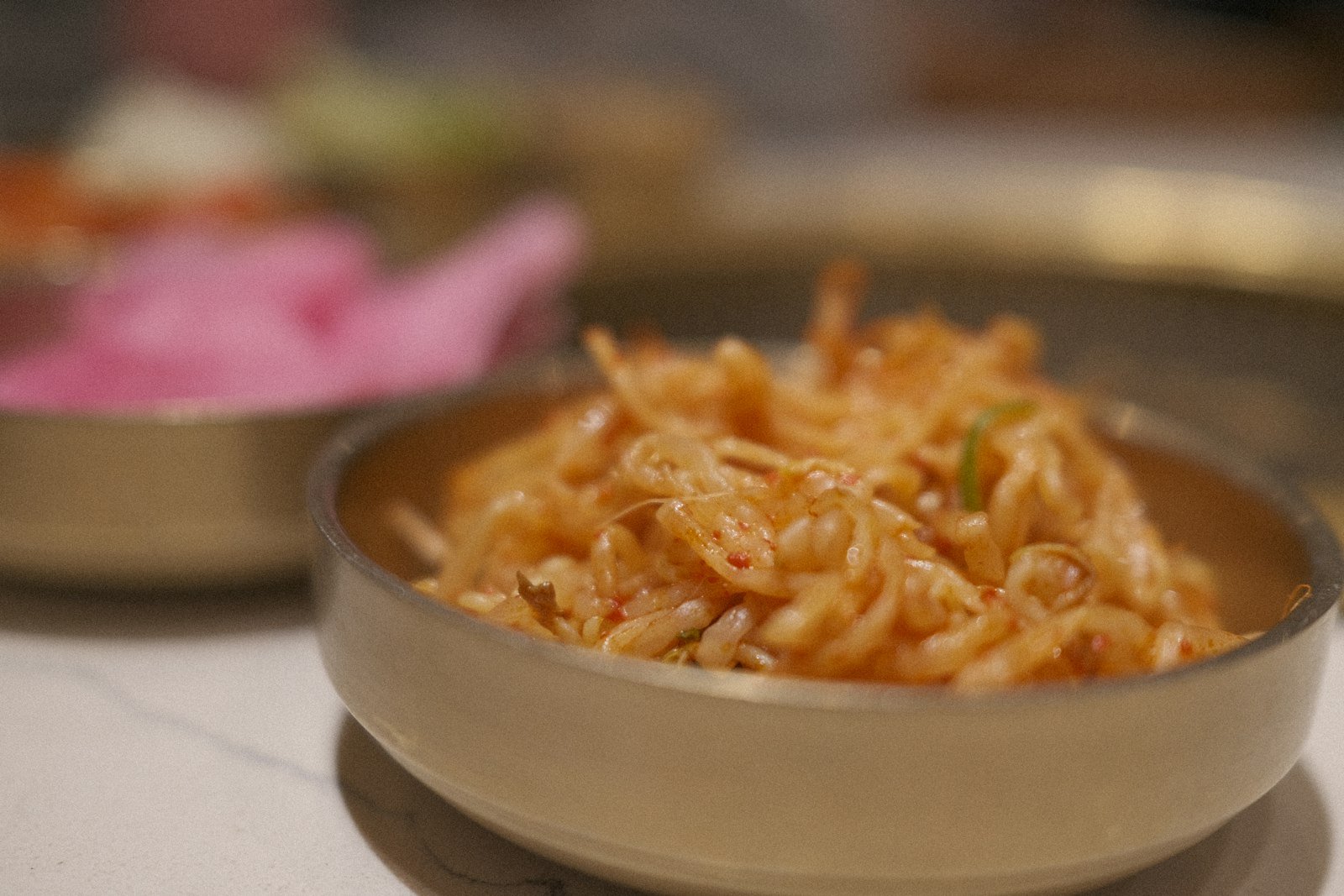 Banchan side dishes in brass bowls at a Korean restaurant, served free with the meal