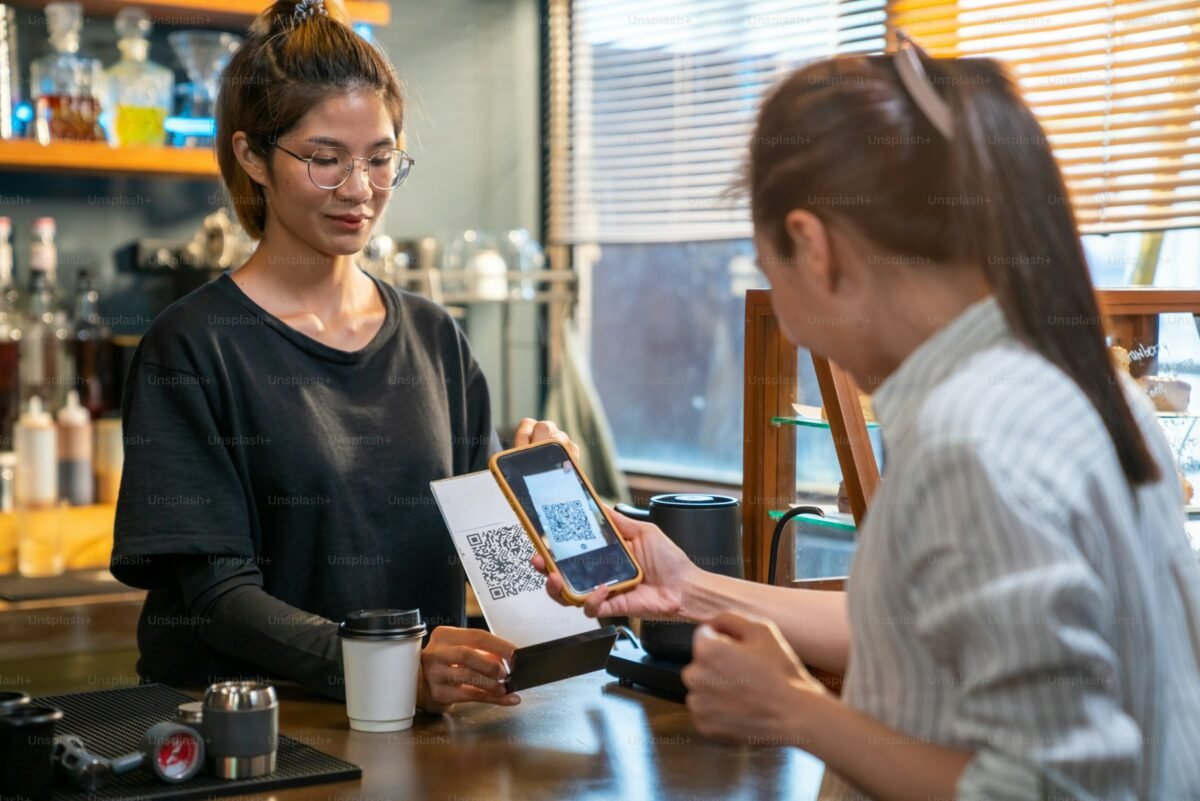 Customer paying with a QR code on a phone at a cafe counter, where Kakao Pay for foreigners is often confusing