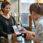 Customer paying with a QR code on a phone at a cafe counter, where Kakao Pay for foreigners is often confusing